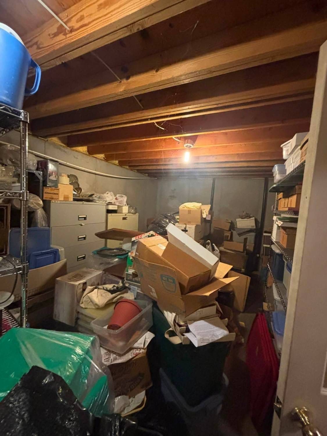 Basement storage room packed with boxes, bins and shelving before a cleanout