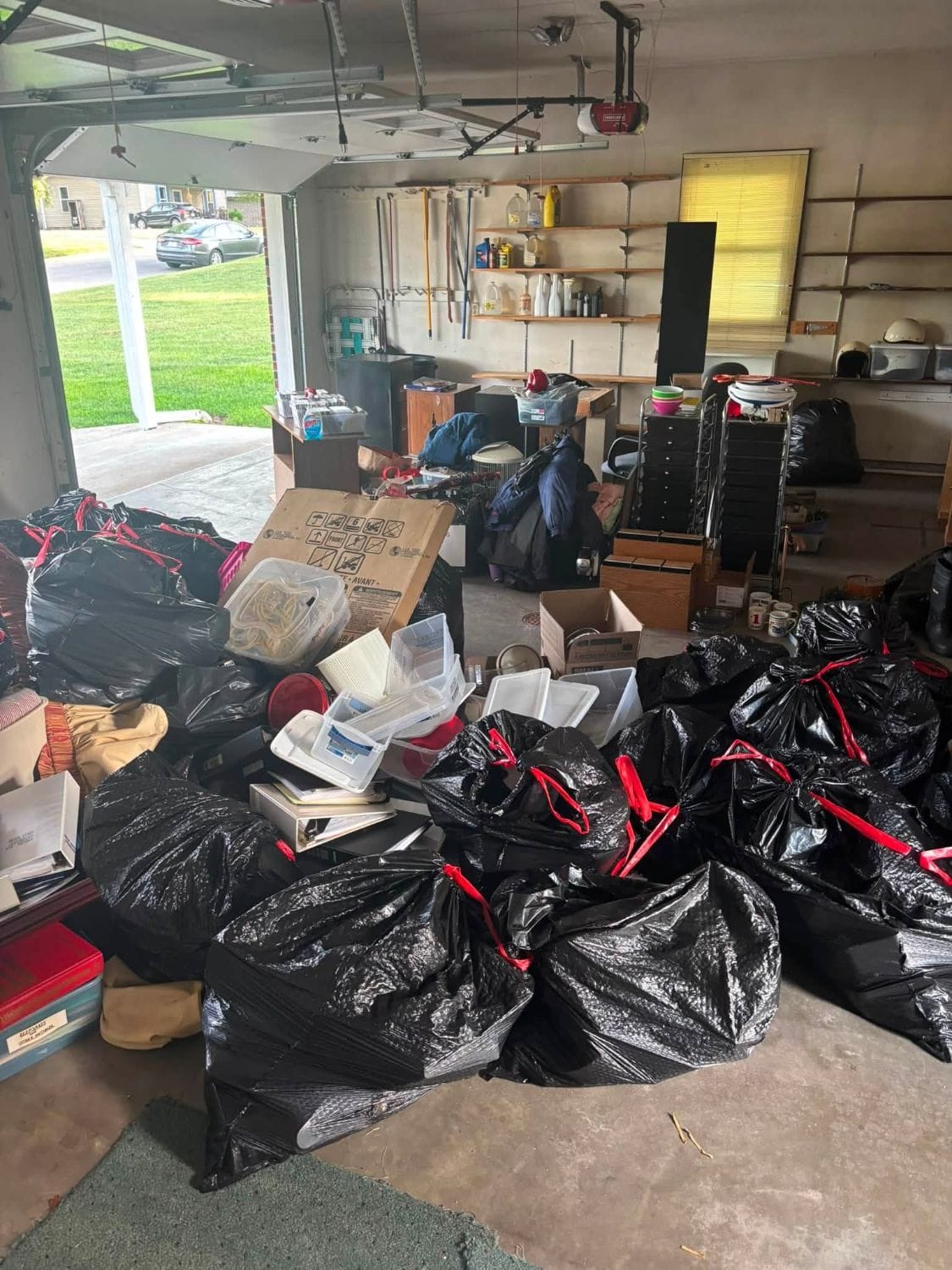 Garage floor covered in bagged household items and boxes ready for removal