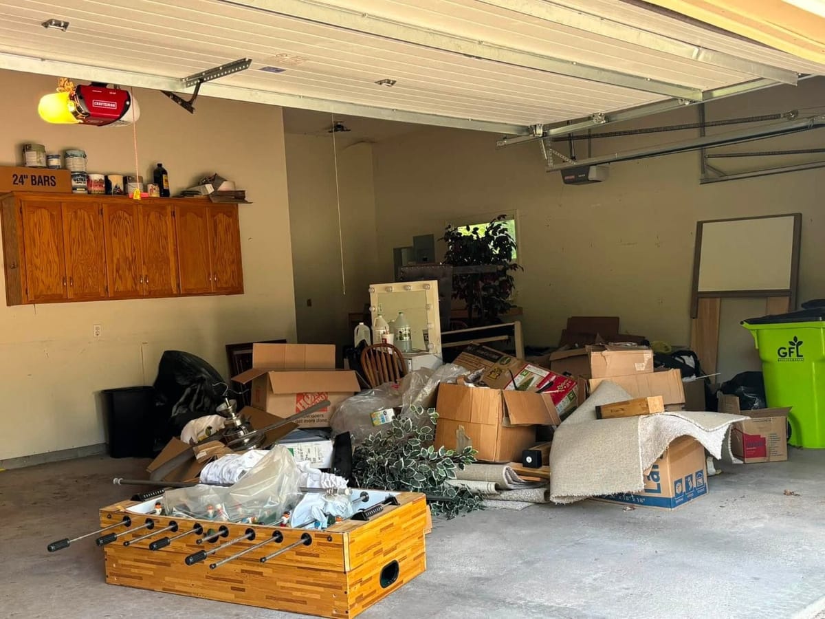 Garage piled with boxes, carpet, a foosball table and household items before a cleanout
