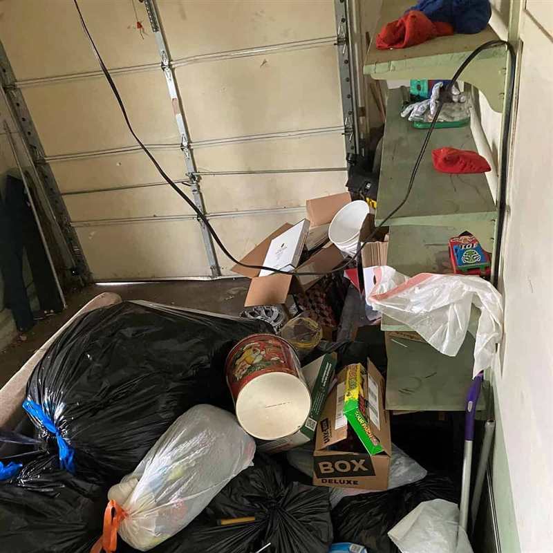 Garage filled with trash bags, boxes and loose items before an A Plus Junk Removal cleanout