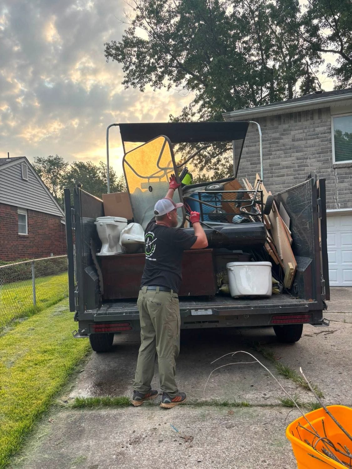 A Plus crew member loading toilets, a cabinet and other junk into a trailer at sunset